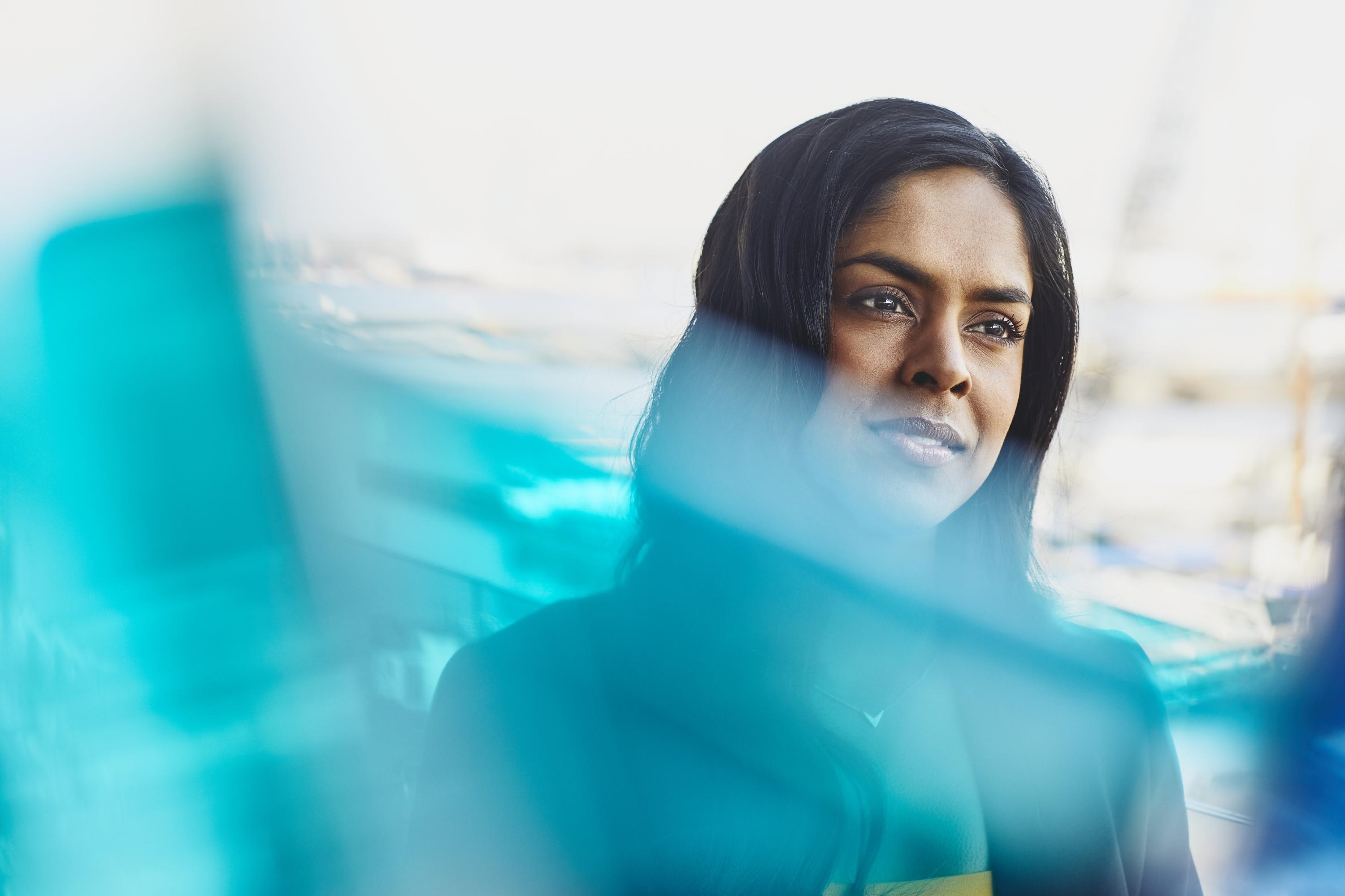 Young woman in harbor. India. Primary color: blue.