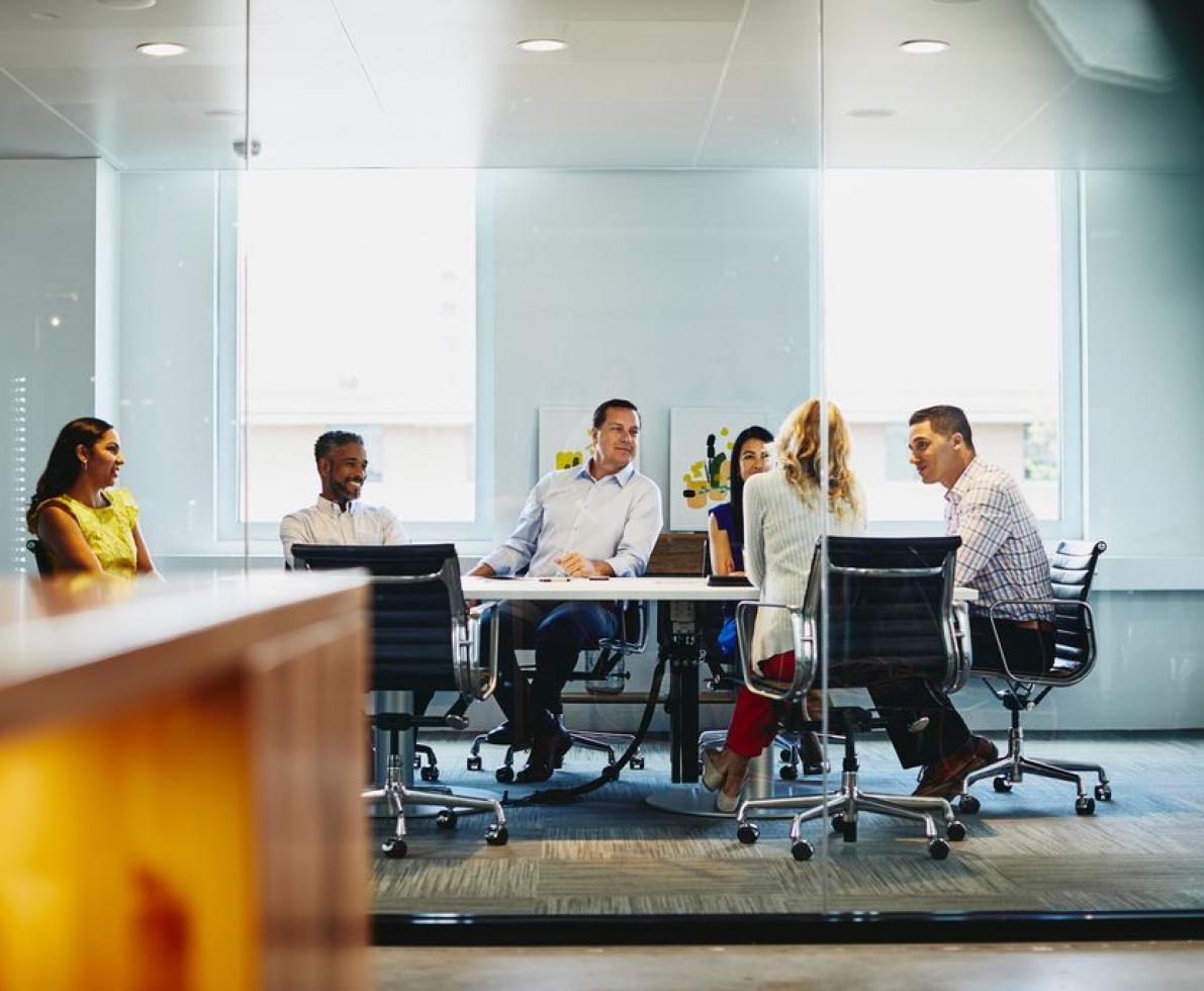 Six (6) people in business meeting. Happy faces. Good atmosphere. Inside. Office.